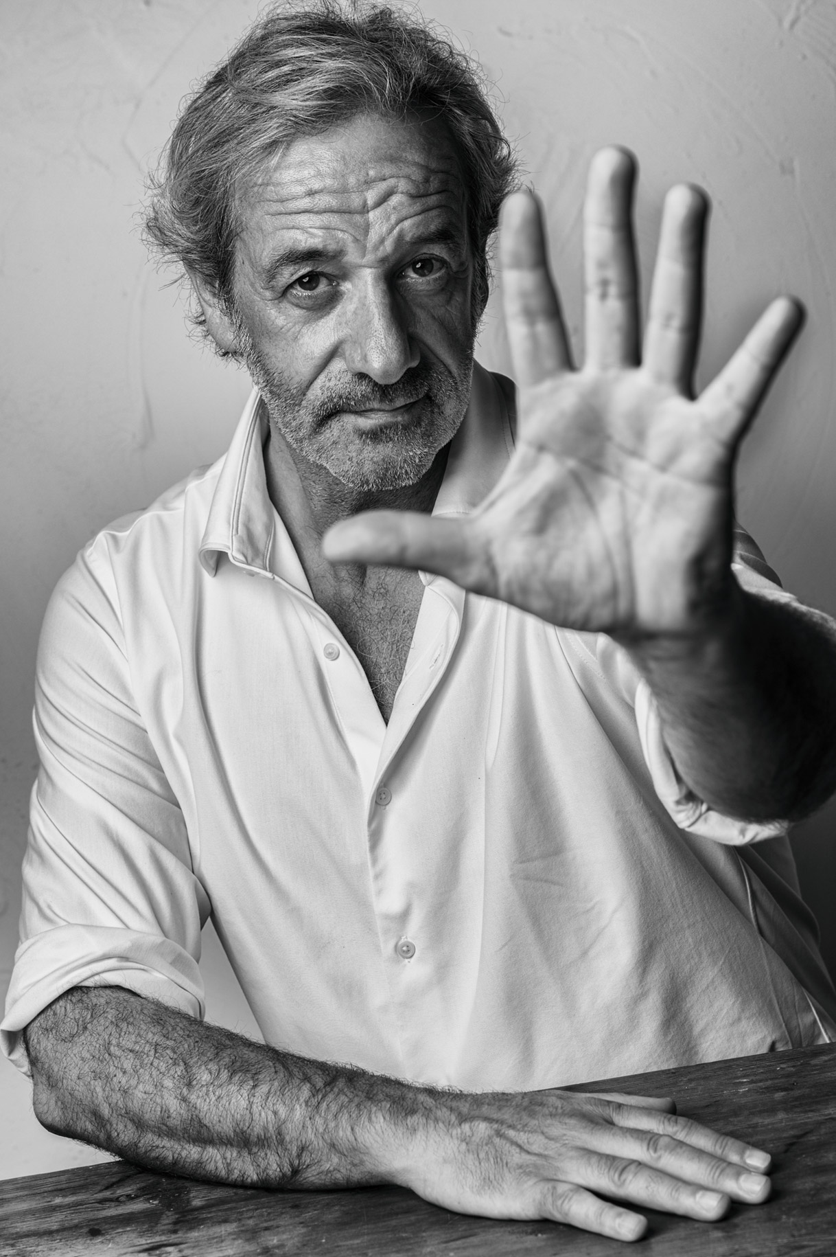 Retrato en blanco y negro del pintor Iñaki Moreno con la palma de la mano abierta hacia la cámara