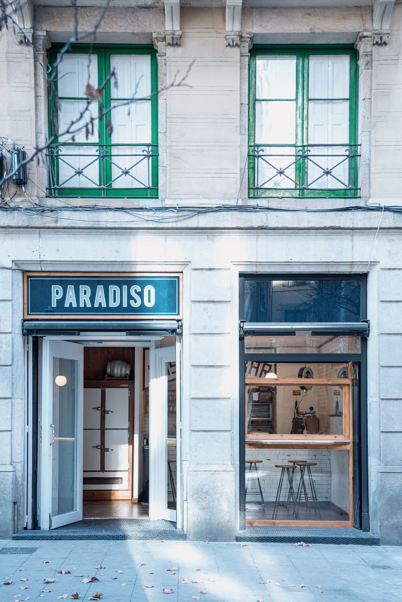Fachada azul del Paradiso Pastrami Bar con ventanas de carpintería verde