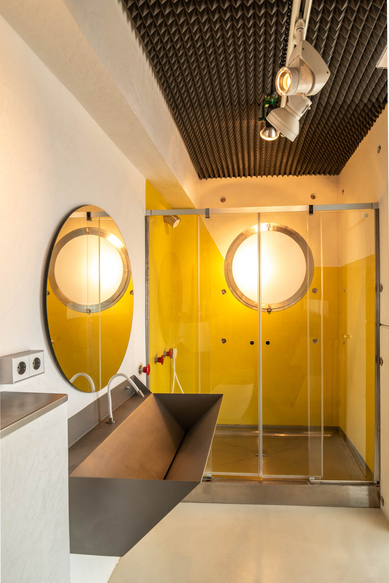Baño con mampara amarilla translúcida y espejos ovalados retroiluminados