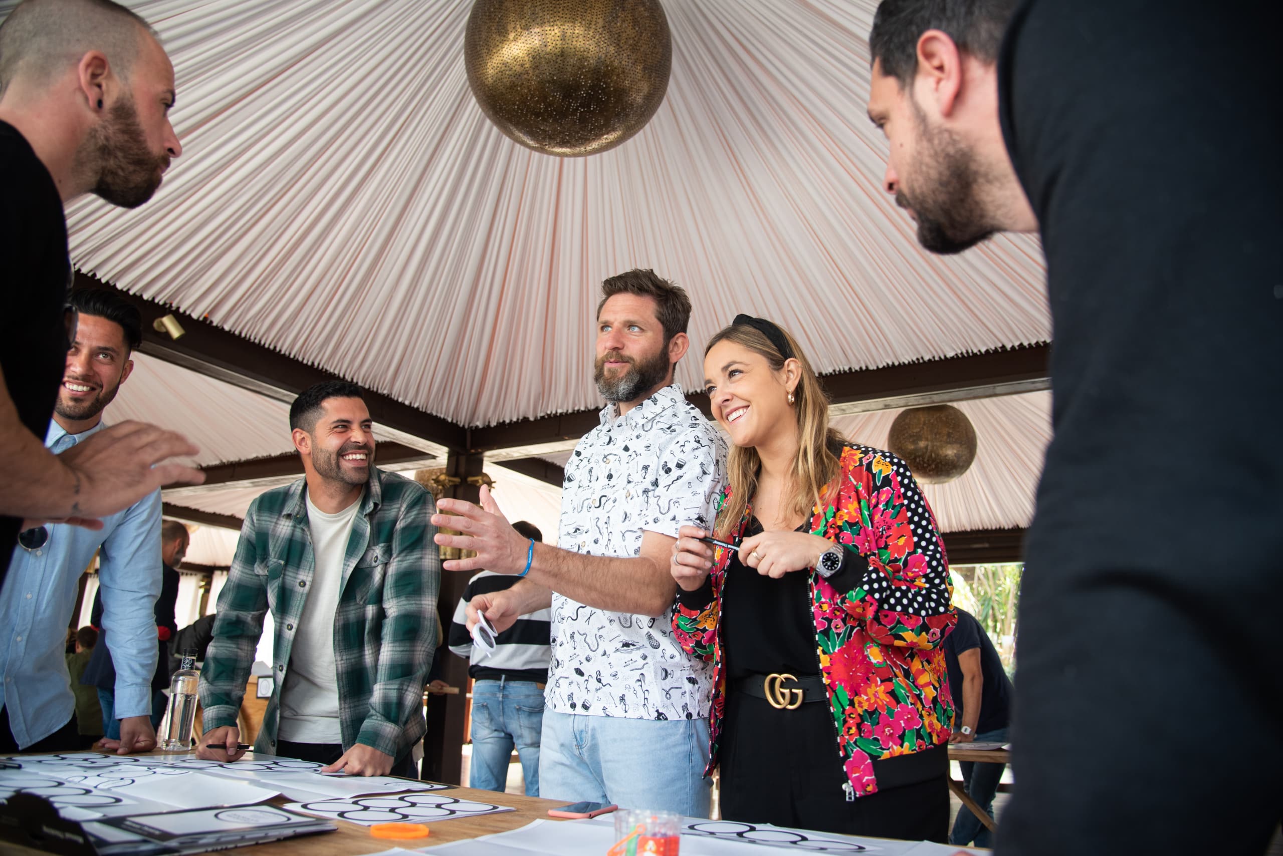 Asistentes conversando durante el taller de coctelería bajo una carpa