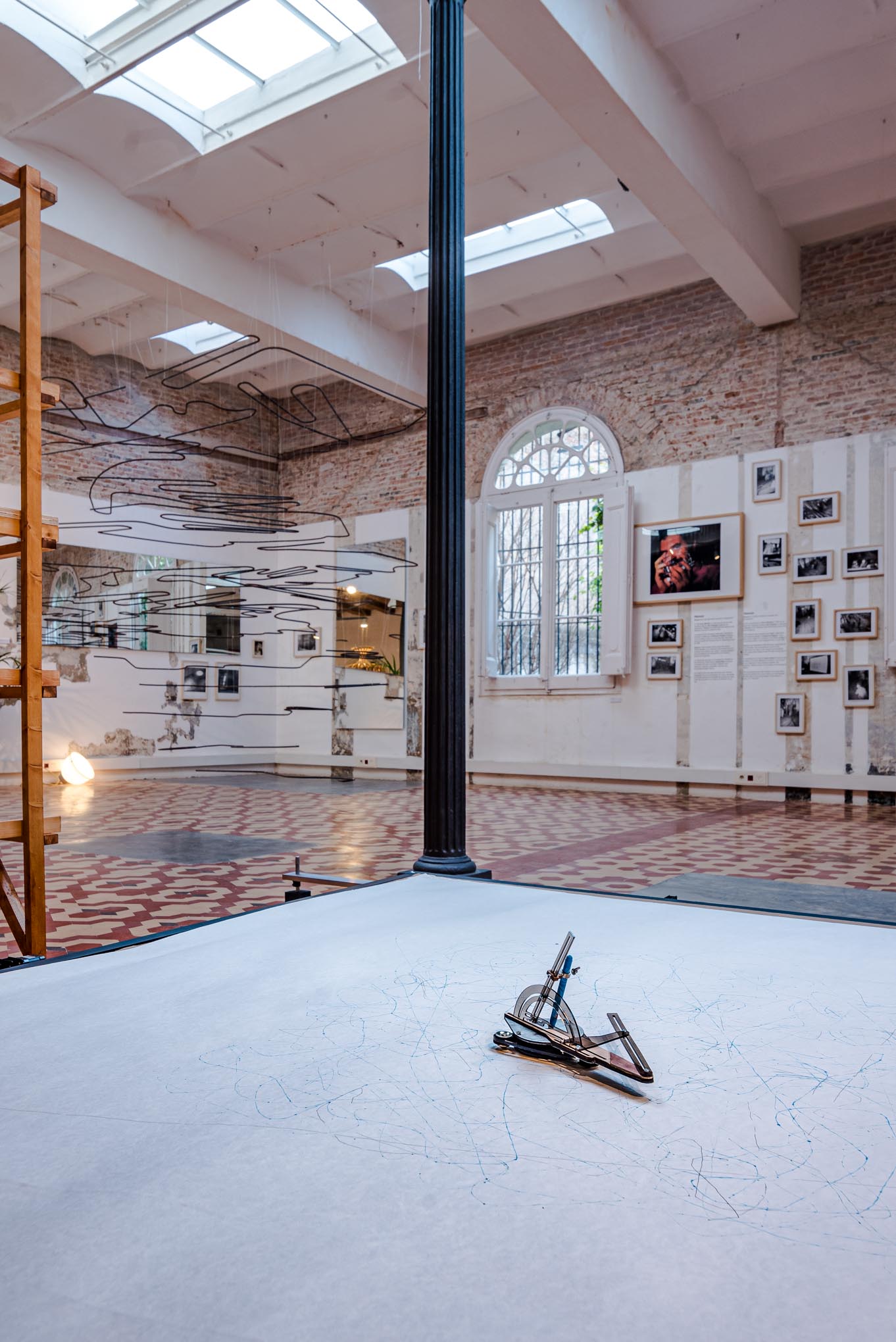 Sala de exposición con paredes de ladrillo, claraboyas y una pieza escultórica en el centro