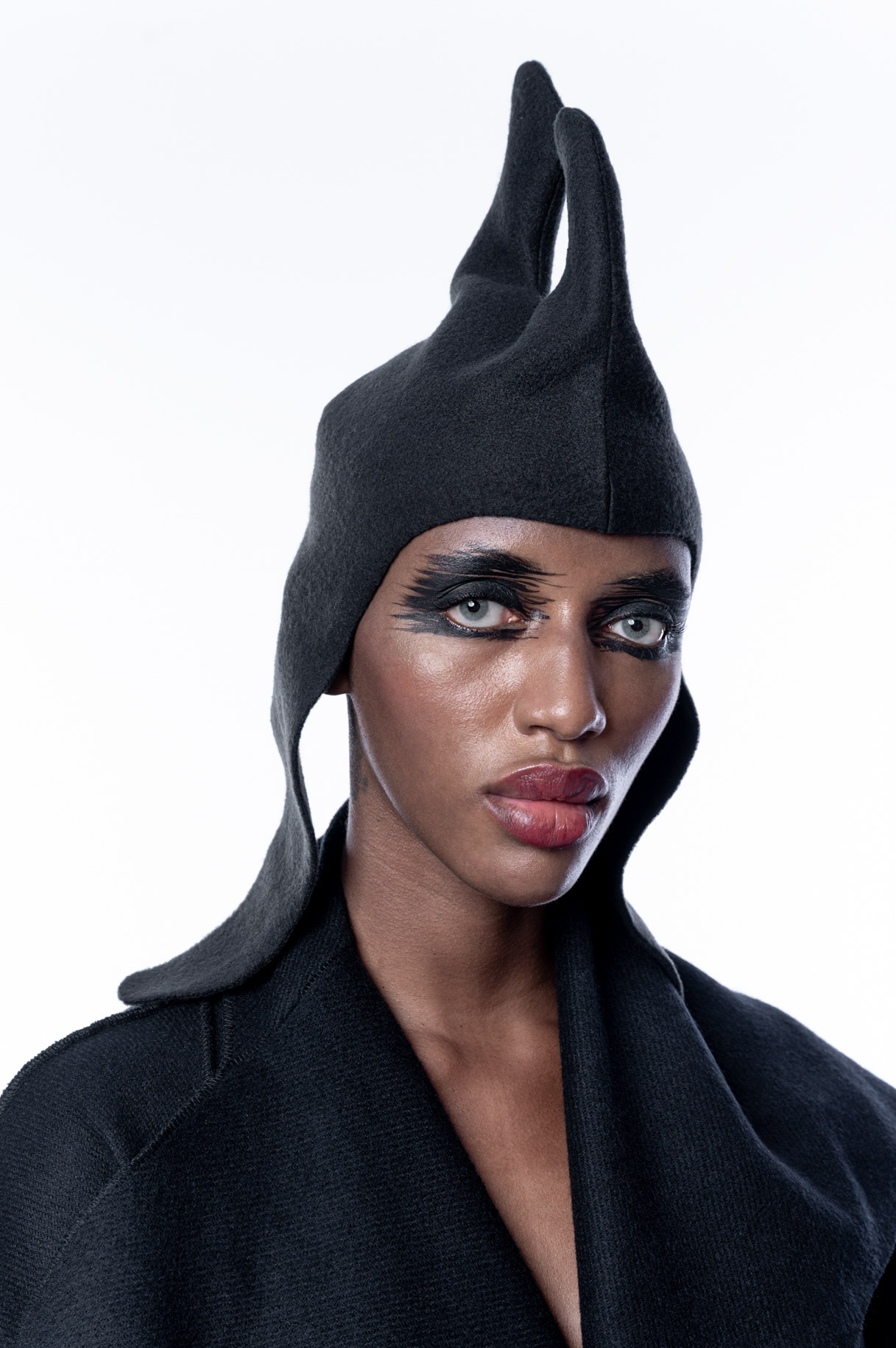 Retrato de modelo con tocado negro de picos y abrigo oscuro