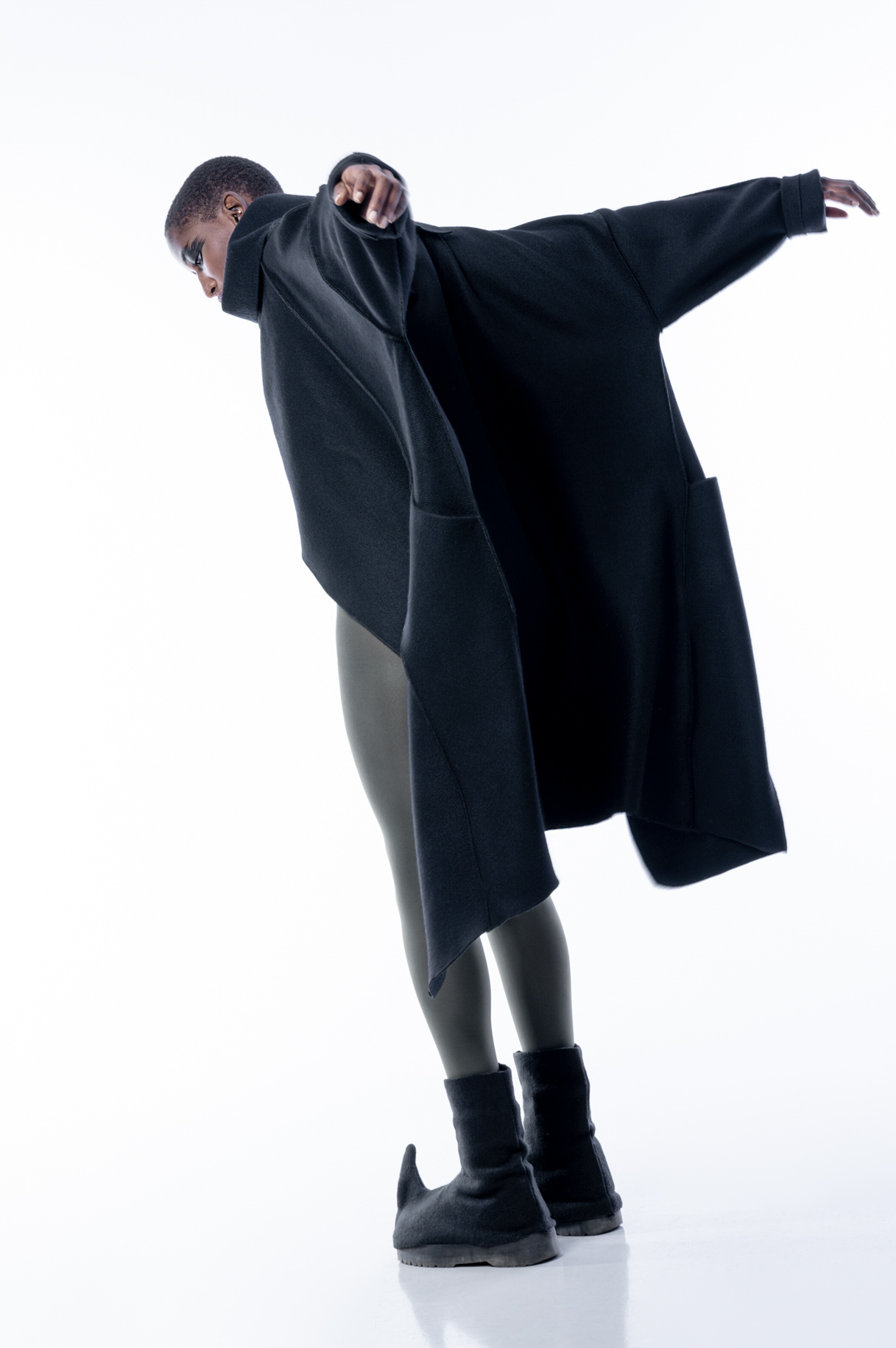 Modelo con abrigo negro oversize y mallas en movimiento