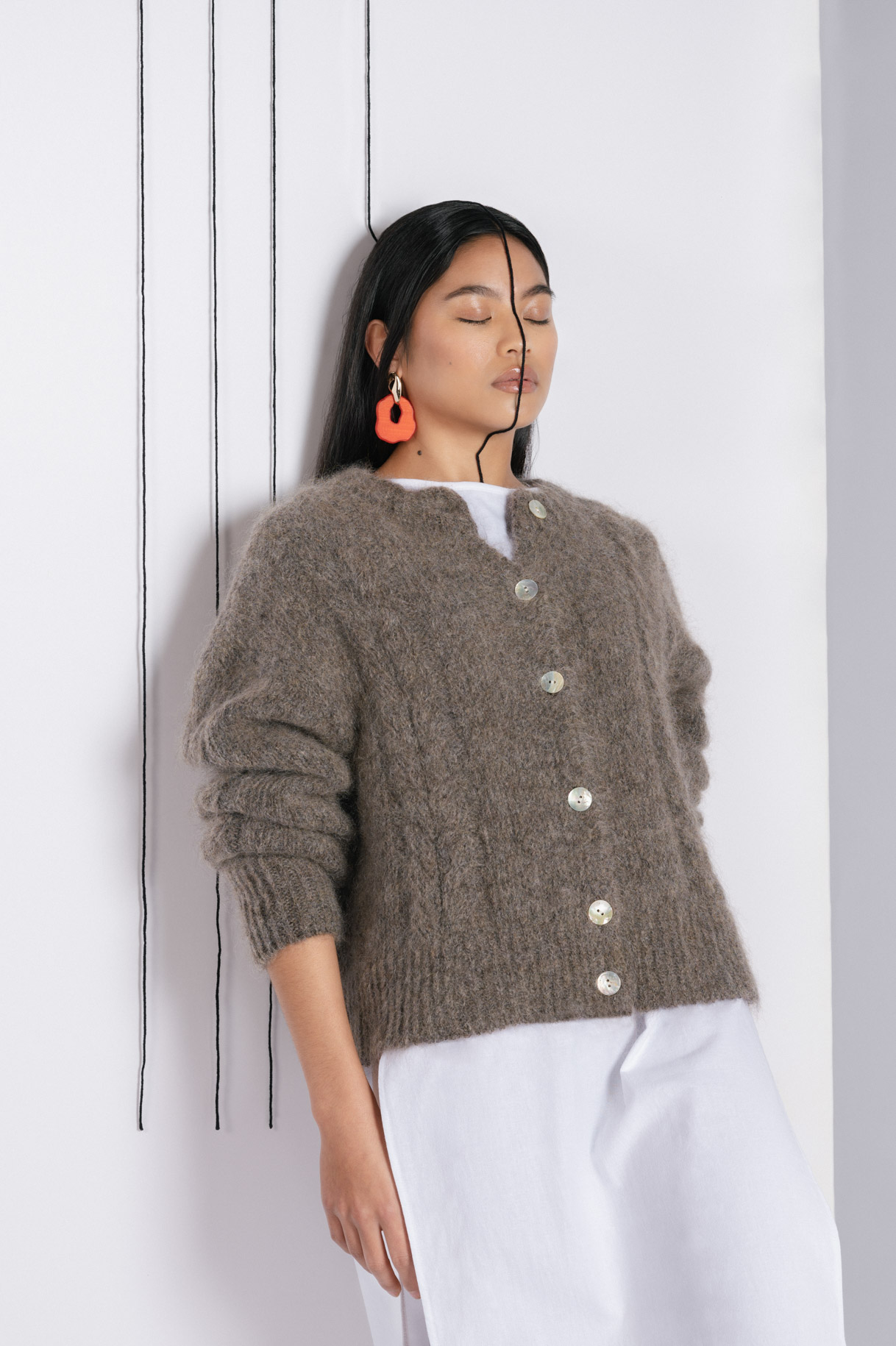 Modelo apoyada en la pared con cárdigan de mohair marrón
